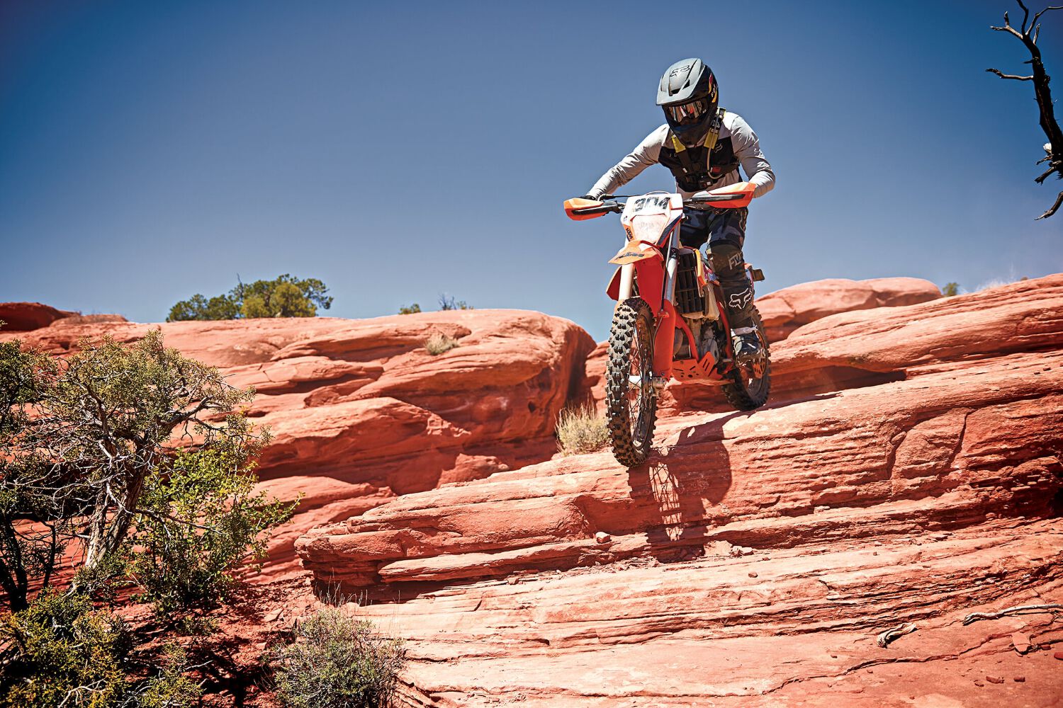 A dirt biking riding down a steep rocky drop.